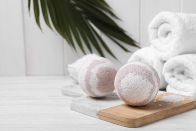 Bath bombs, sea salt and rolled towels on white wooden table, space for text