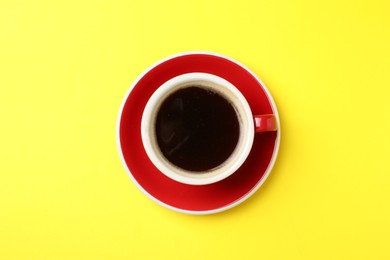 Photo of Aromatic coffee in cup on yellow background, top view