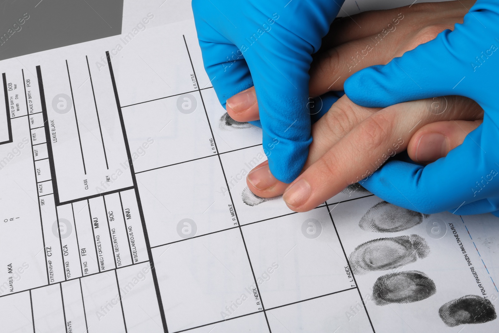 Photo of Investigator taking fingerprints of suspect at table, closeup. Criminal expertise