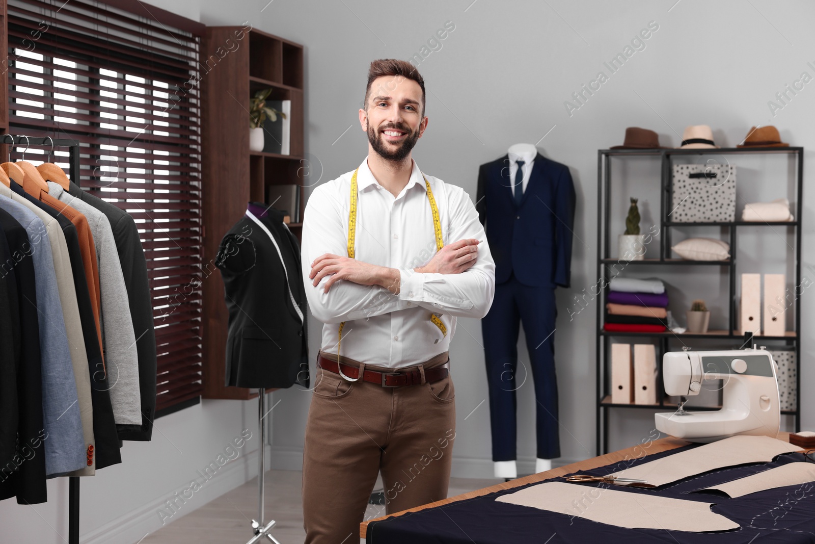 Photo of Professional tailor with measuring tape in workshop