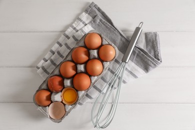 Photo of Fresh raw chicken eggs and whisk on white wooden table, flat lay
