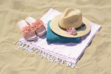 Stylish beach accessories and flower on sand outdoors