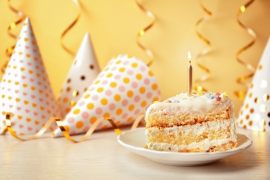 Photo of Slice of delicious birthday cake with candle on table