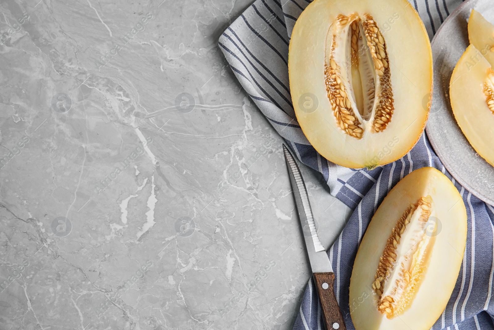 Photo of Tasty cut ripe melon and knife on grey marble table, flat lay. Space for text