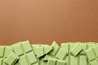 Pieces of tasty matcha chocolate bars on brown background, top view. Space for text