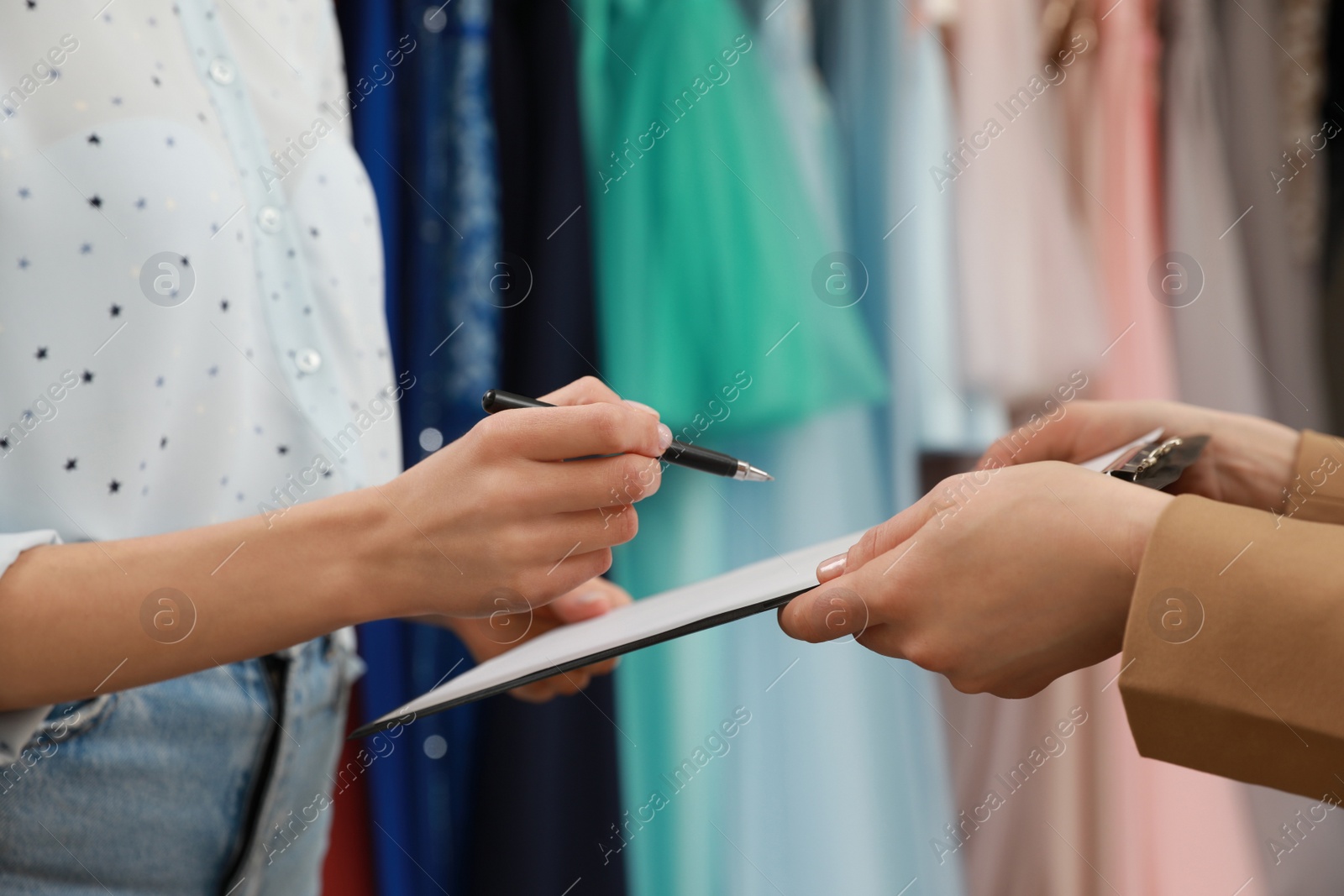Photo of Woman signing rental agreement in clothing salon, closeup