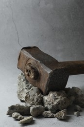 One sledgehammer and pieces of broken stones on grey background, closeup