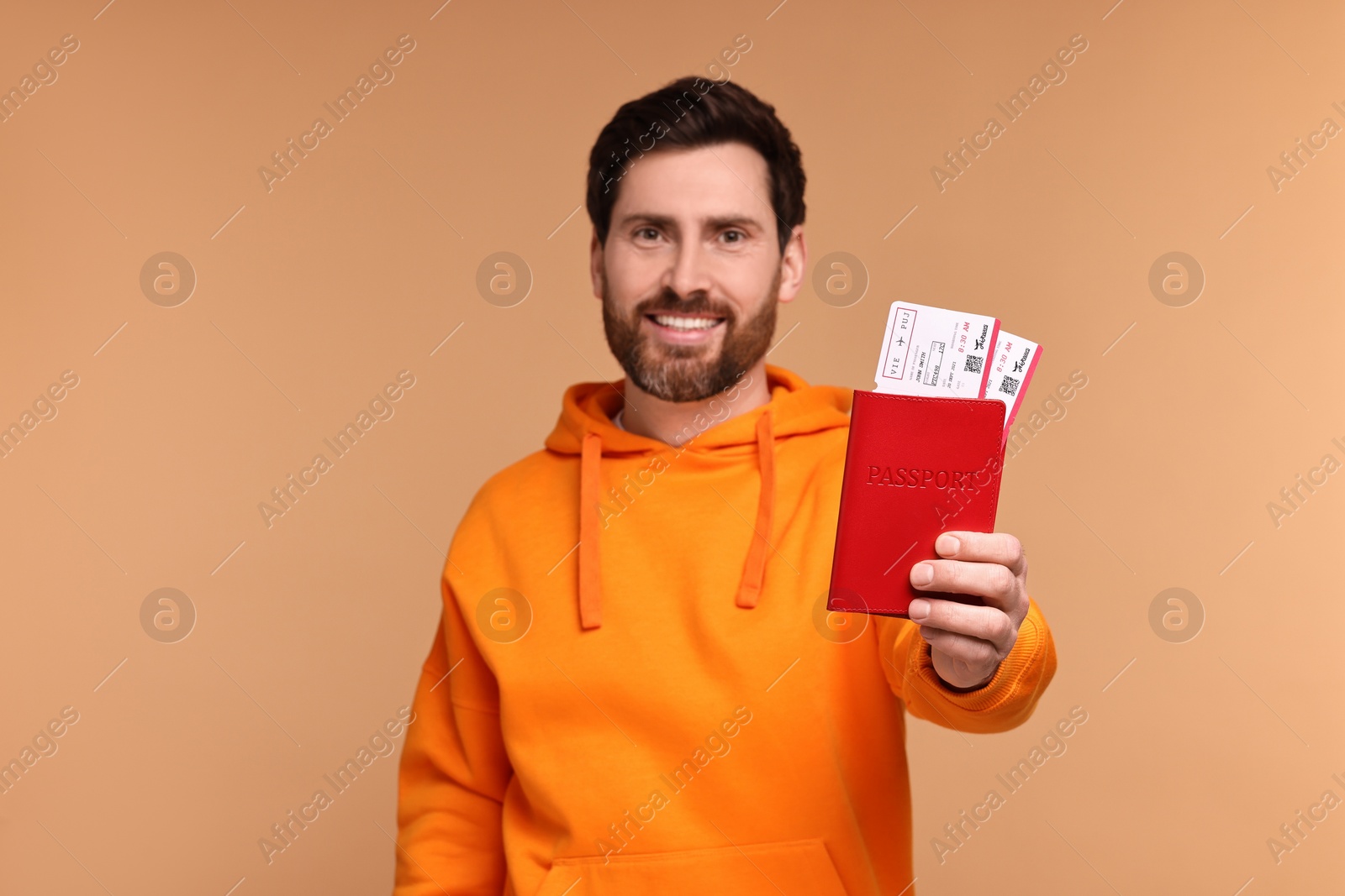 Photo of Smiling man showing passport and tickets on beige background