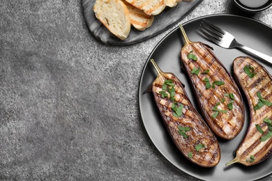 Delicious grilled eggplant halves served on grey table, flat lay. Space for text