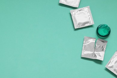 Unpacked condom and packages on turquoise background, flat lay with space for text. Safe sex