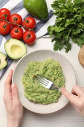 Photo of Woman preparing delicious guacamole at white wooden table, top view