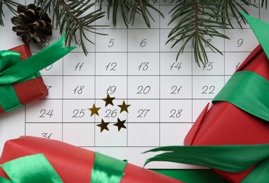 Photo of Gifts on calendar with marked Boxing Day date, flat lay