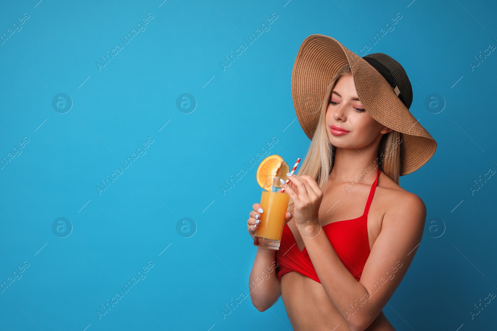 Photo of Pretty young woman wearing stylish bikini with cocktail on blue background. Space for text