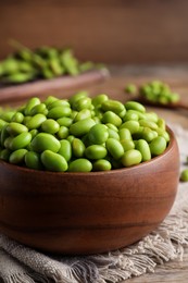 Photo of Bowl of delicious edamame beans on wooden table, closeup