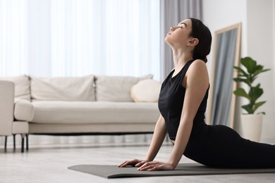 Girl practicing cobra asana on yoga mat at home. Bhujangasana pose