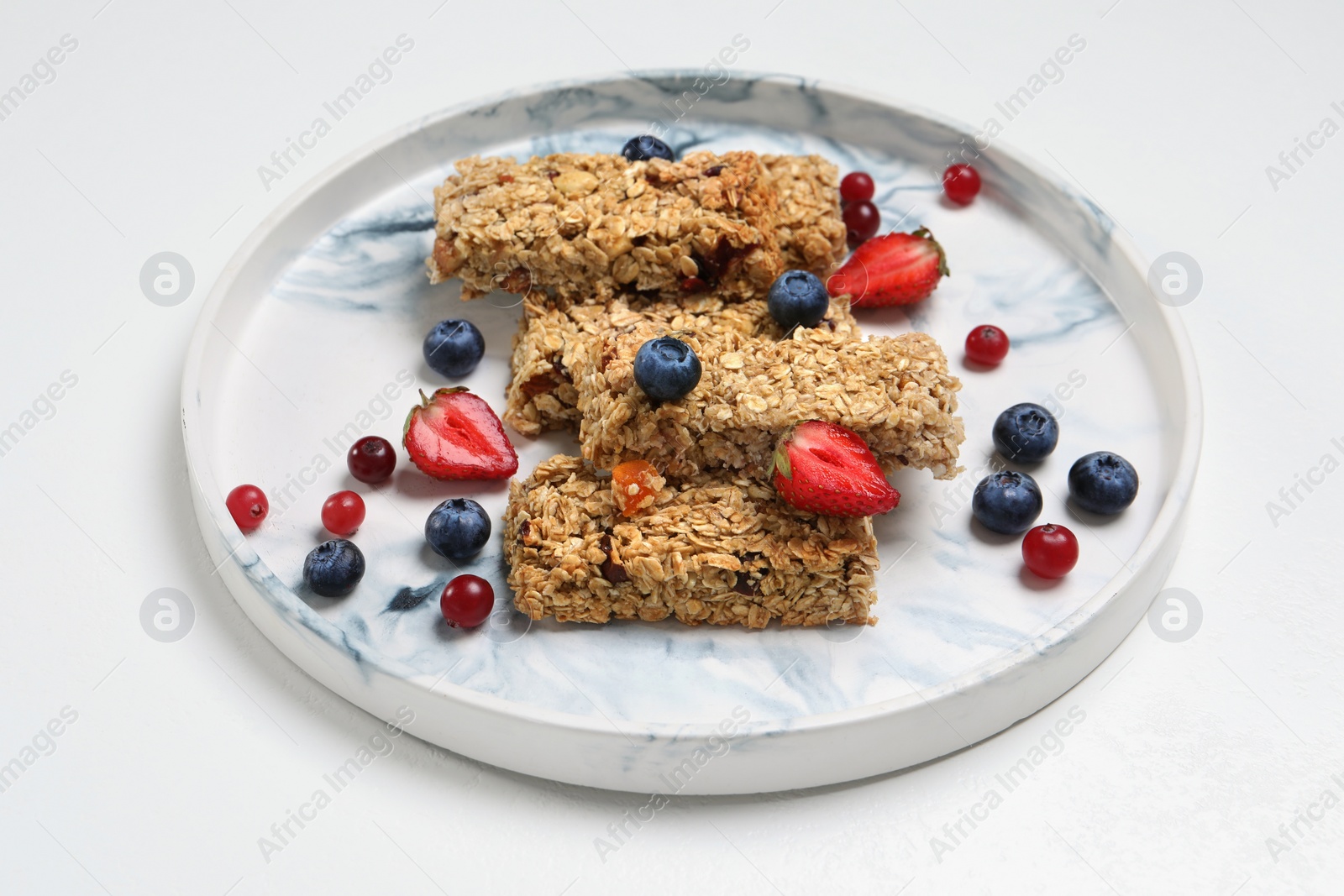 Photo of Tasty granola bars and berries on white background