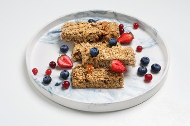 Tasty granola bars and berries on white background