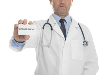 Doctor holding business card with word HEMORRHOID on white background, closeup