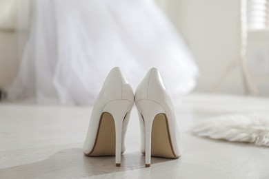 Photo of White wedding shoes on floor in room, back view