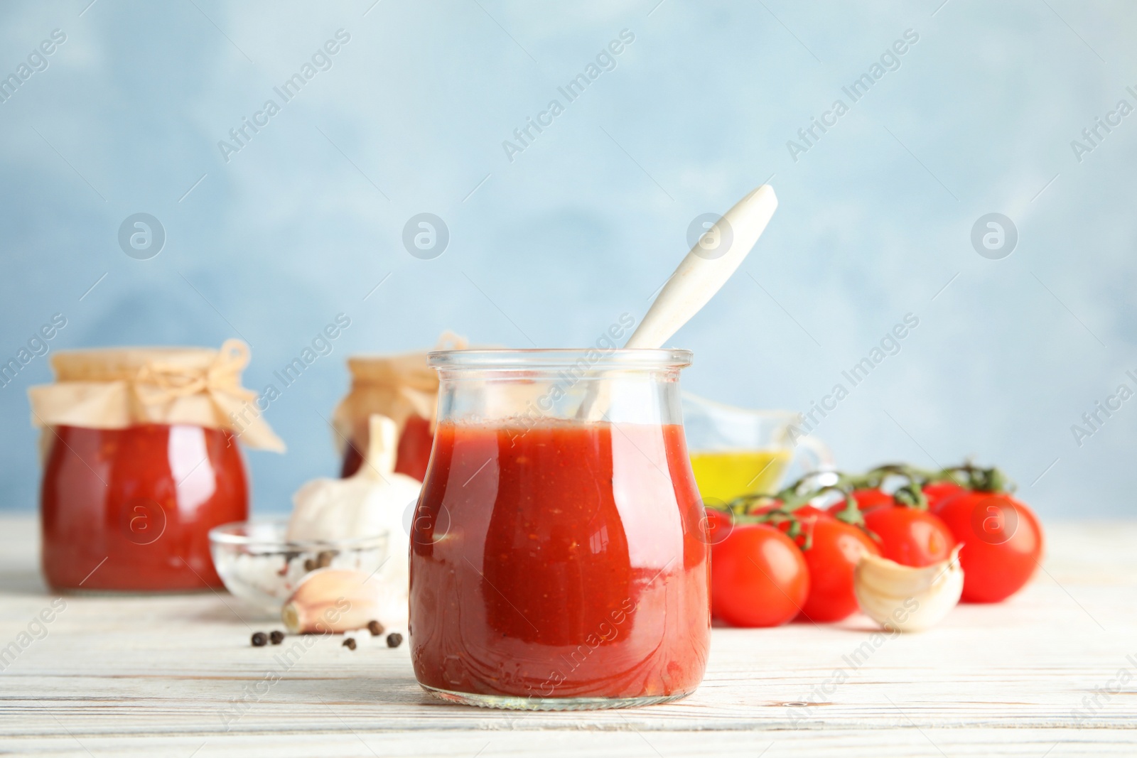 Photo of Composition with tomato sauce, spices and vegetables on table against color background. Space for text