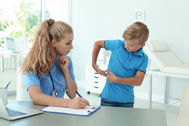 Female medical assistant consulting child in clinic