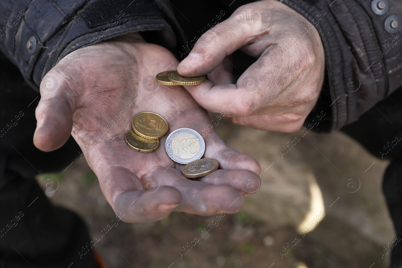 Photo of Poor homeless man holding coins outdoors, closeup