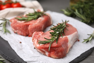 Photo of Fresh raw meat with rosemary on slate plate, closeup