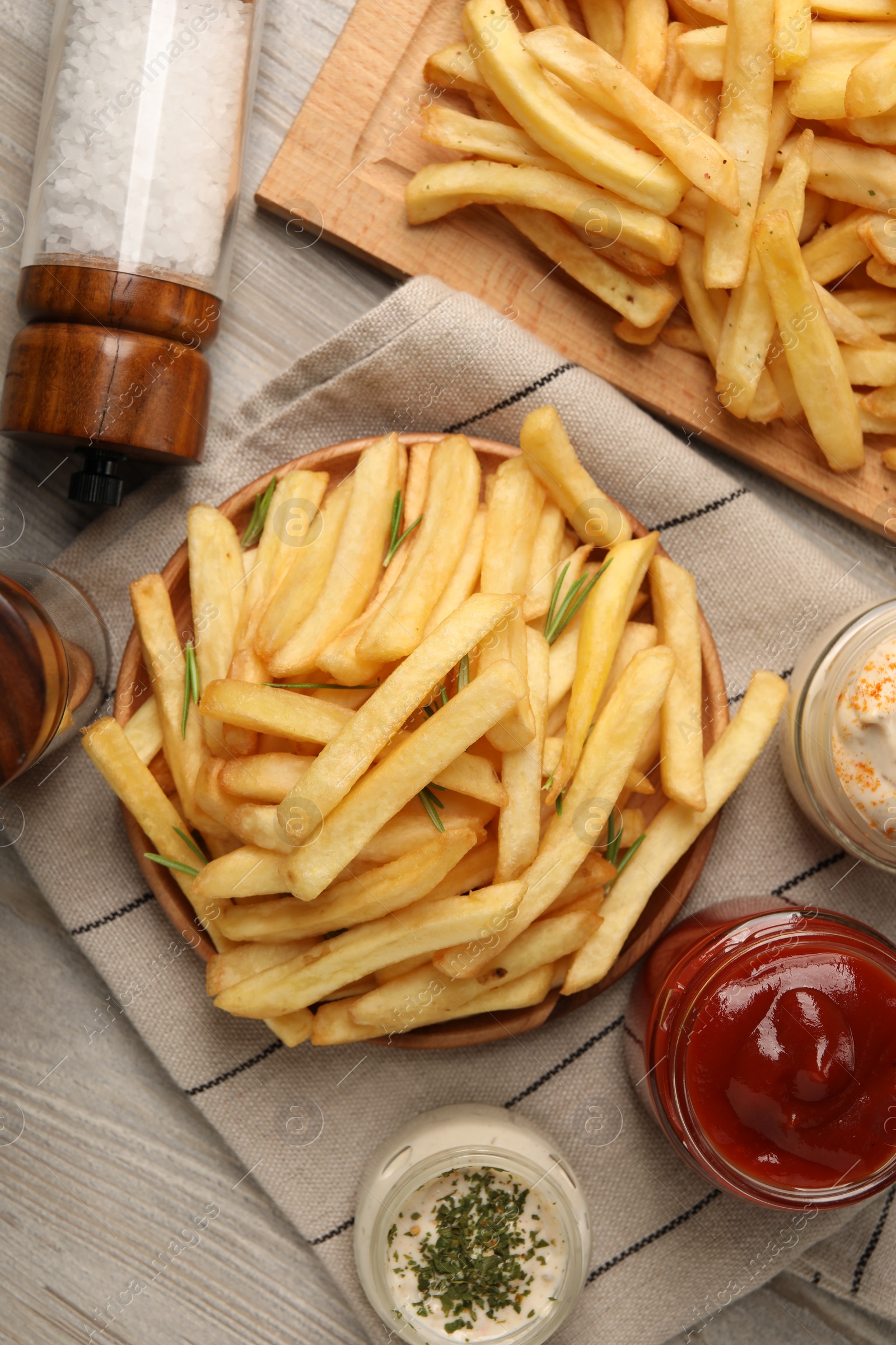 Photo of Delicious french fries served with sauces on light wooden table, flat lay