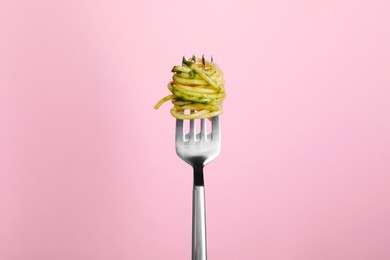 Fork with tasty pasta on pink background