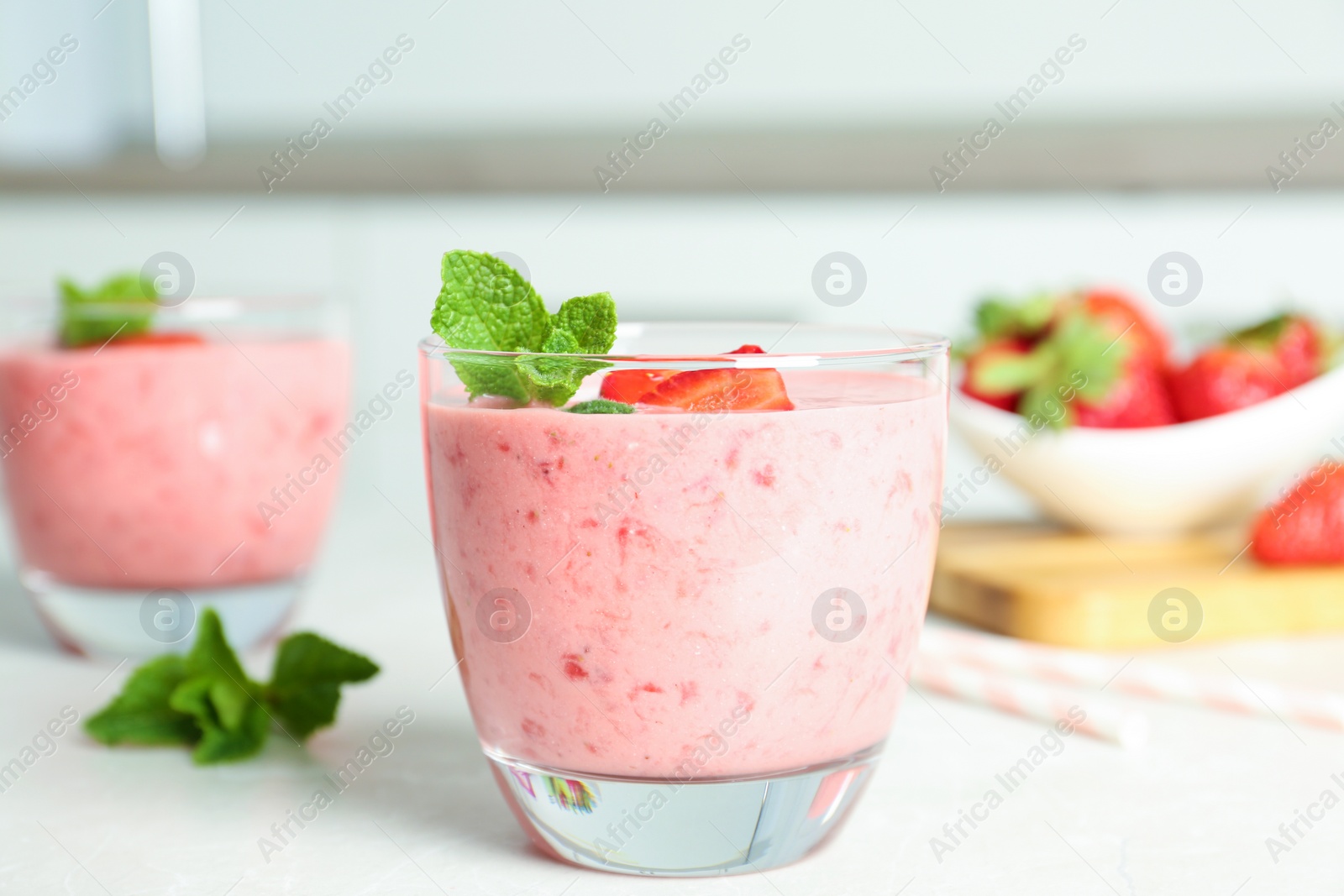 Photo of Tasty strawberry smoothie with mint in glass on light grey table