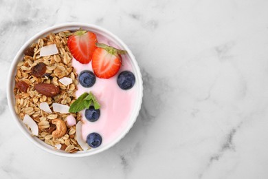 Photo of Tasty granola, yogurt and fresh berries in bowl on white marble table, top view with space for text. Healthy breakfast