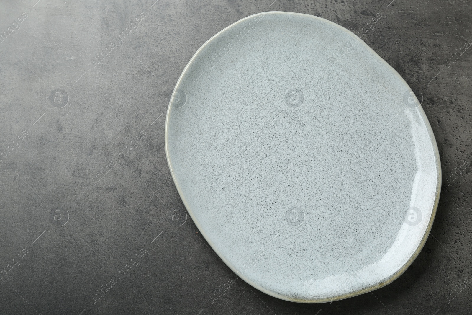 Photo of Empty ceramic plate on grey table, top view. Space for text