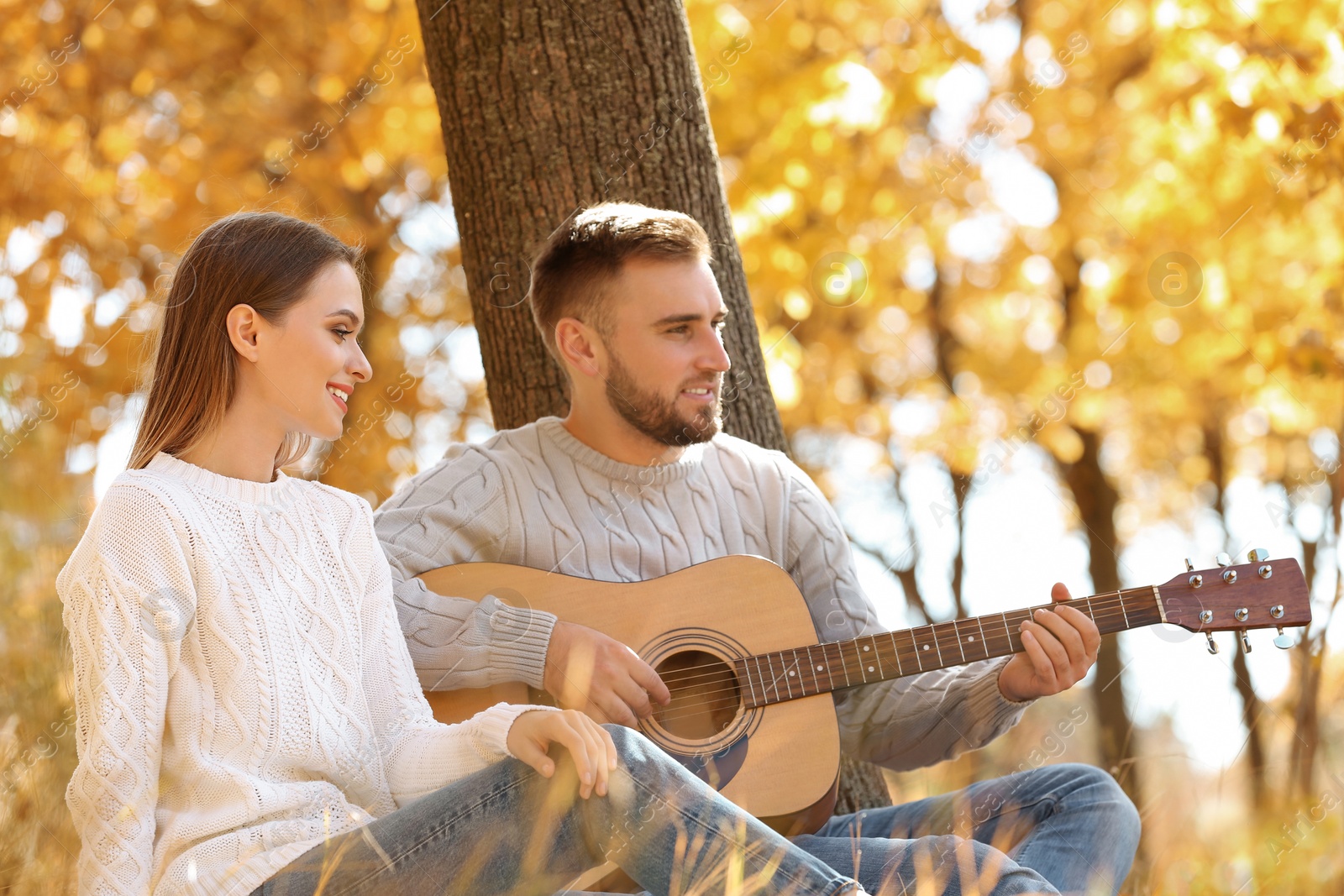 Photo of Young couple with guitar in autumn park