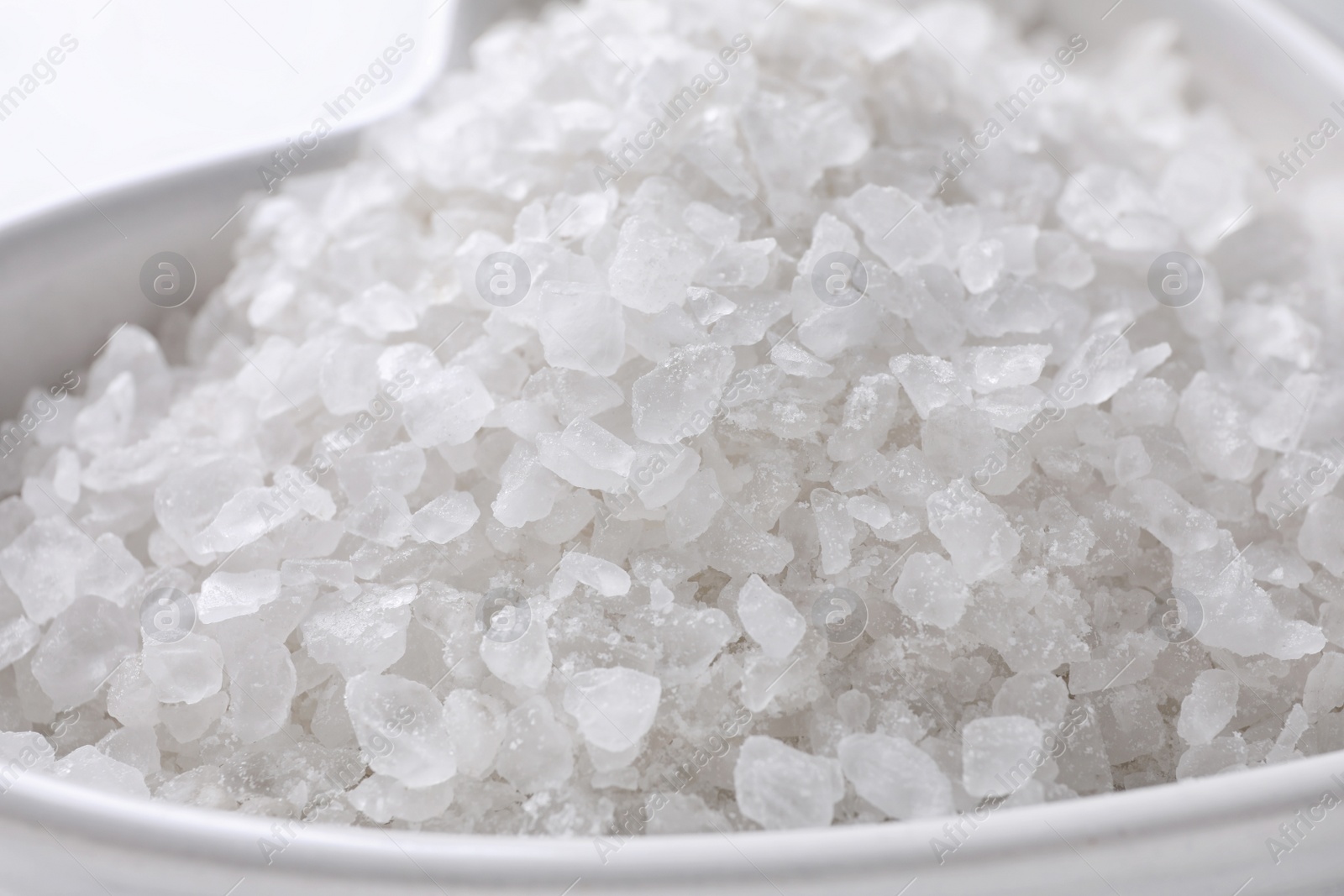 Photo of Natural white sea salt in bowl, closeup view. Spa treatment