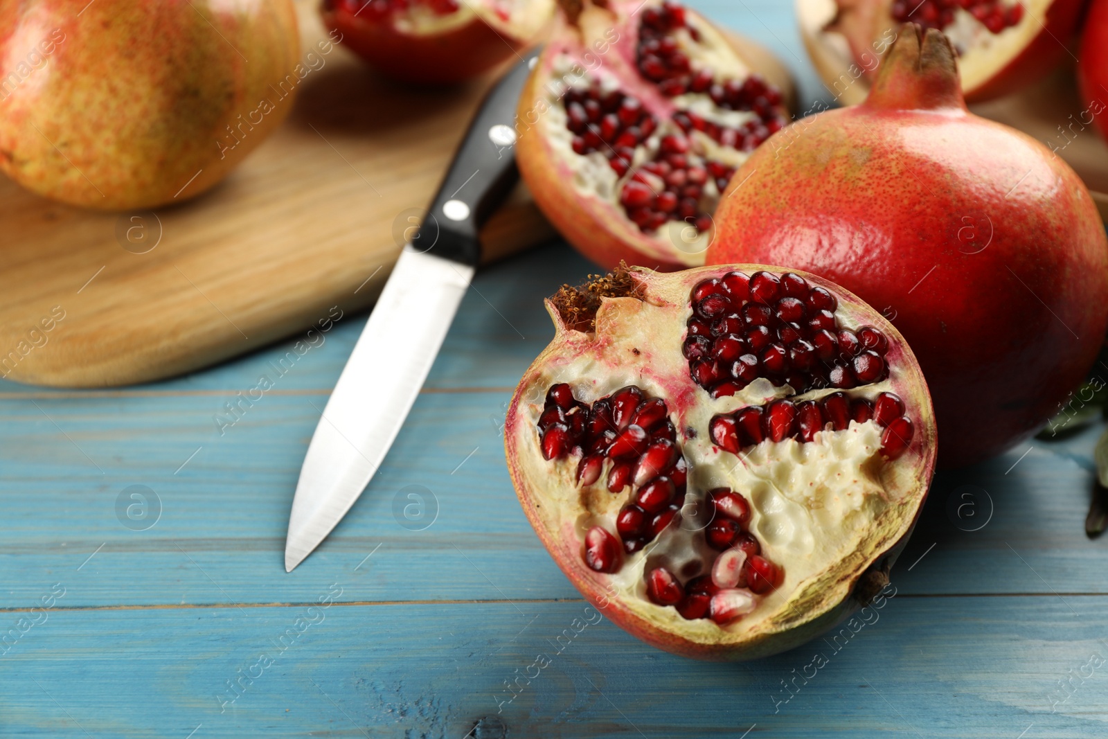 Photo of Ripe pomegranates on light blue wooden table