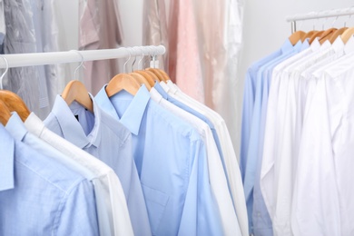 Photo of Racks with clean clothes on hangers after dry-cleaning indoors