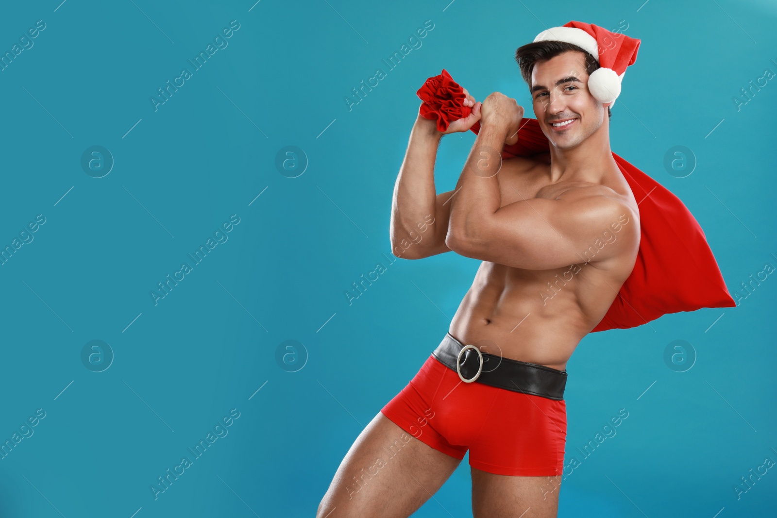 Photo of Sexy shirtless Santa Claus on blue background, space for text