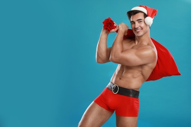 Sexy shirtless Santa Claus on blue background, space for text