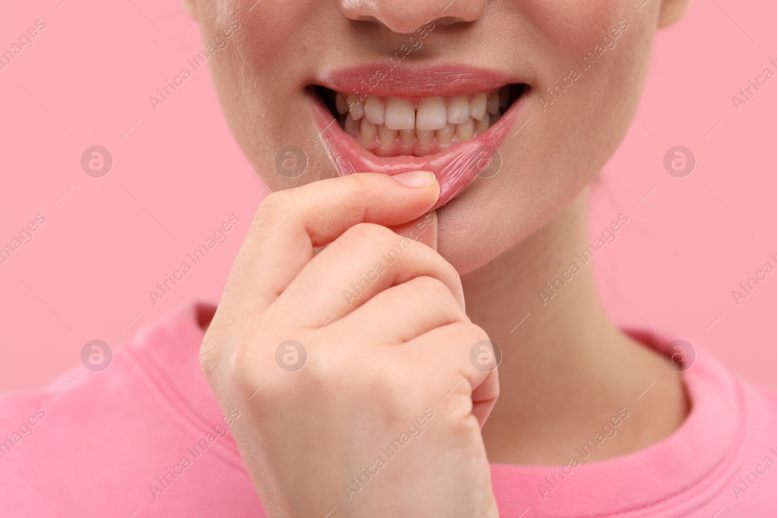 Photo of Beautiful woman showing her clean teeth on pink background, closeup