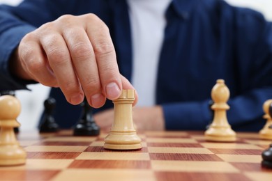 Photo of Man with rook game piece playing chess at checkerboard, closeup