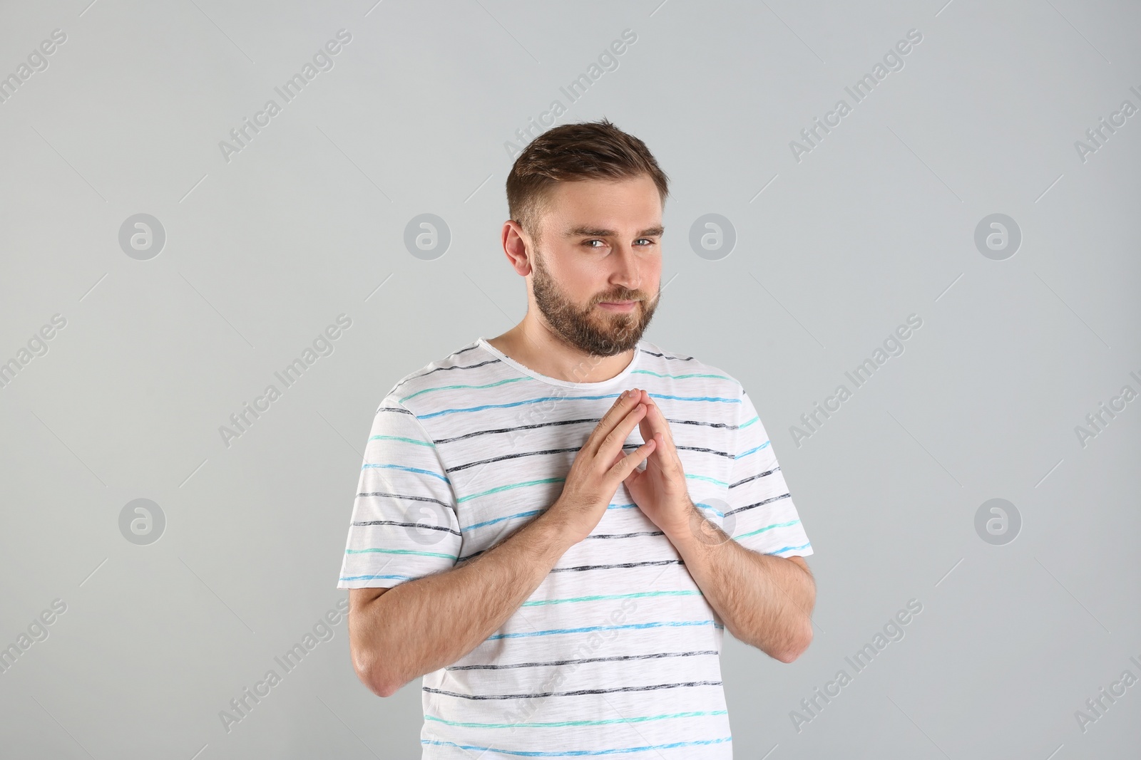 Photo of Greedy young man rubbing hands on light grey background