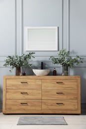 Photo of Modern bathroom interior with stylish mirror, eucalyptus branches, vessel sink and wooden vanity