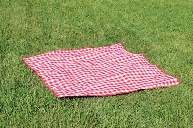 Checkered picnic tablecloth on fresh green grass outdoors