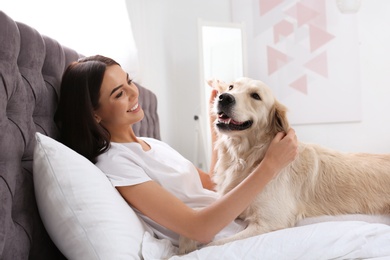 Young woman and her Golden Retriever dog on bed at home