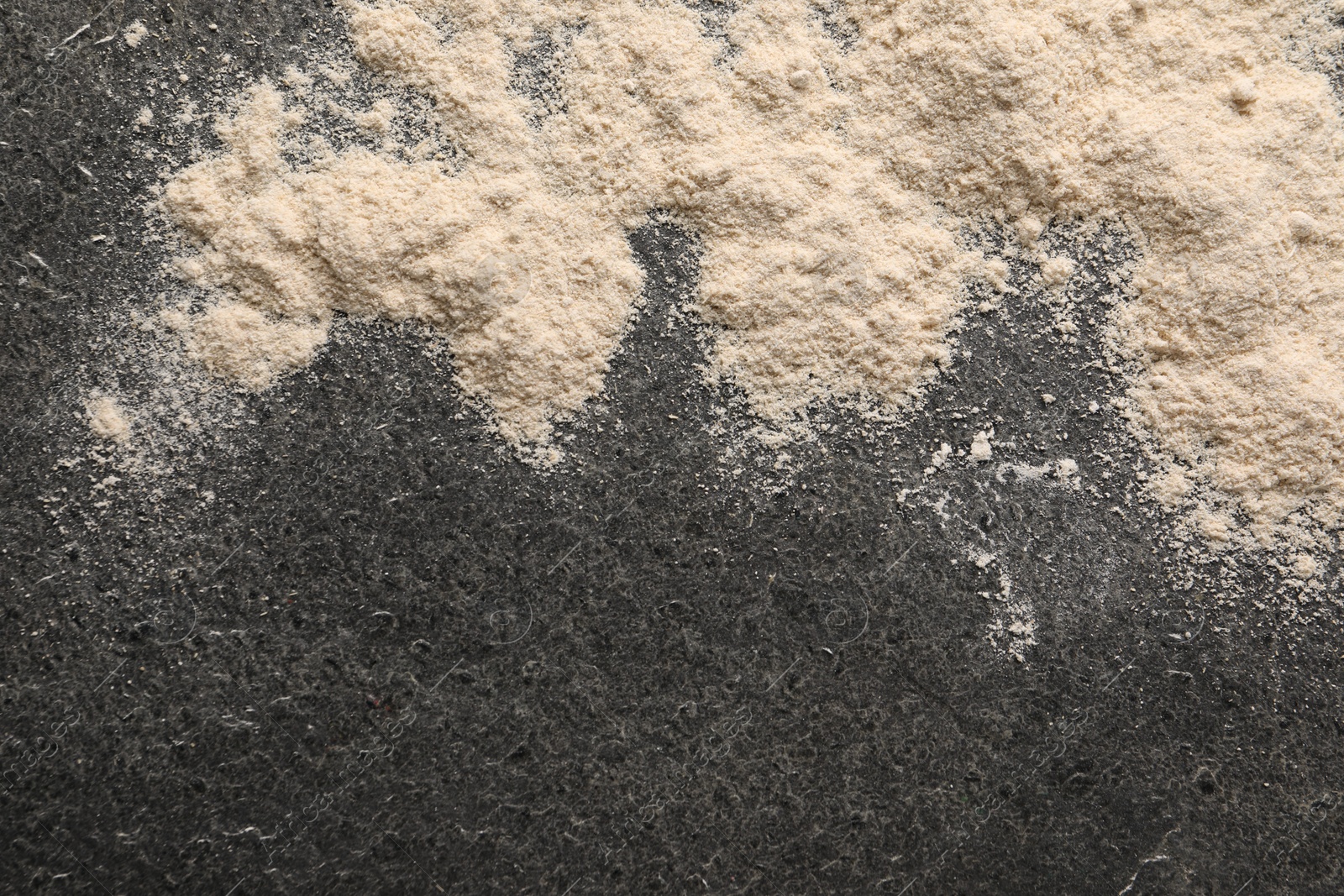 Photo of Scattered flour on grey textured table, top view. Space for text