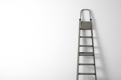 Photo of Metal stepladder on white background. Space for text