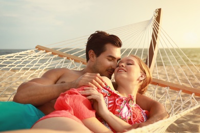 Beautiful young couple resting in hammock at sea beach