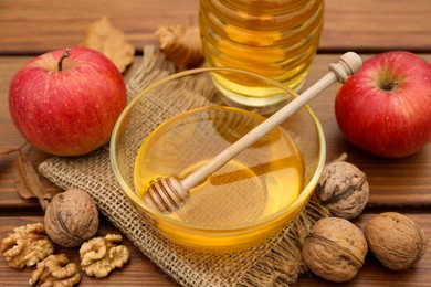 Photo of Fresh aromatic honey, apples and walnuts on wooden table, closeup