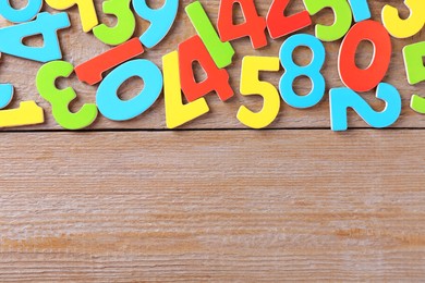 Colorful numbers on wooden table, flat lay. Space for text