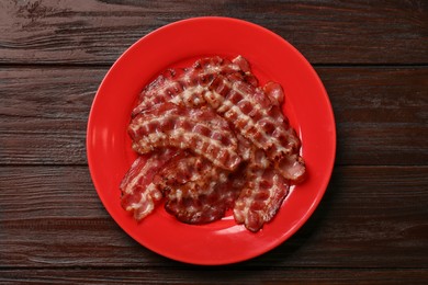 Photo of Plate with fried bacon slices on wooden table, top view